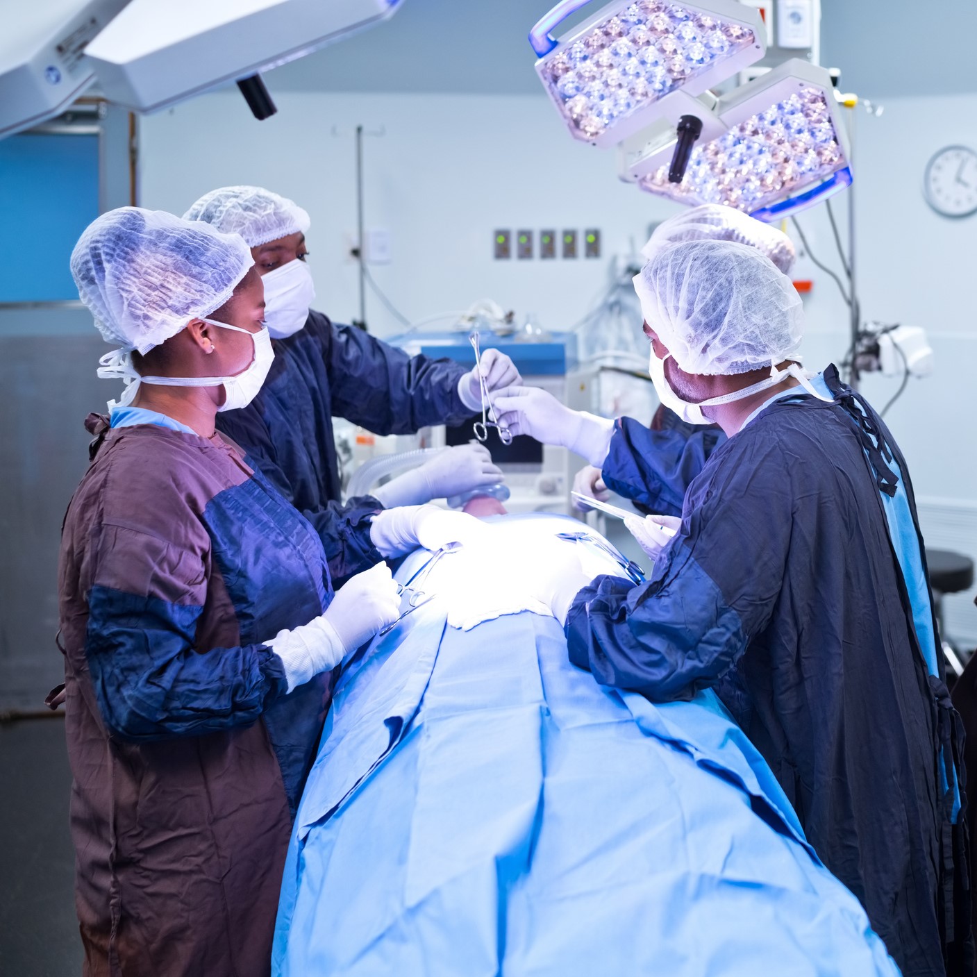 Team of healthcare workers operating illuminated patient in emergency room at hospital