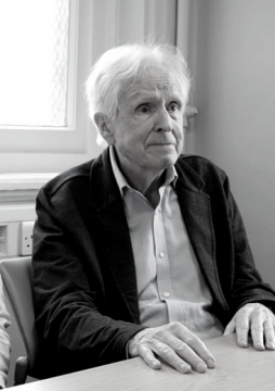 Elderly person seated indoors with window in background