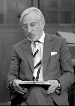 Person in a suit holding a folder, seated