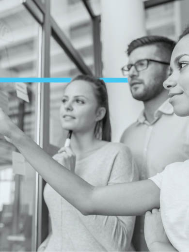 Three individuals working collaboratively looking at a wall.