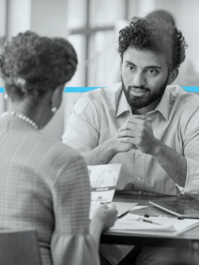 Man and woman sitting across a table discussing a paper.