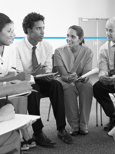 Five medical professionals in scrubs having a discussion