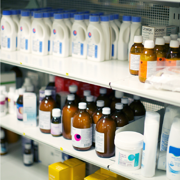 Shelves stocked with medical supplies including bottles, boxes, and containers labelled with items like 'Ucerax'